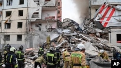 Foto yang dirilis oleh Gubernur wilayah Belgorod Vyacheslav Gladkov di media sosial pada 12 Mei 2024, menunjukkan pekerja darurat Rusia memeriksa gedung apartemen yang sebagian runtuh setelah serangan rudal Ukraina, di kota Belgorod.