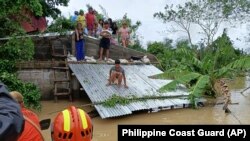 Người dân leo lên mái nhà để tránh lũ lụt và chờ được giải cứu ở Libon, tỉnh Albay, Philippines, vào ngày 23 tháng 10 năm 2024.